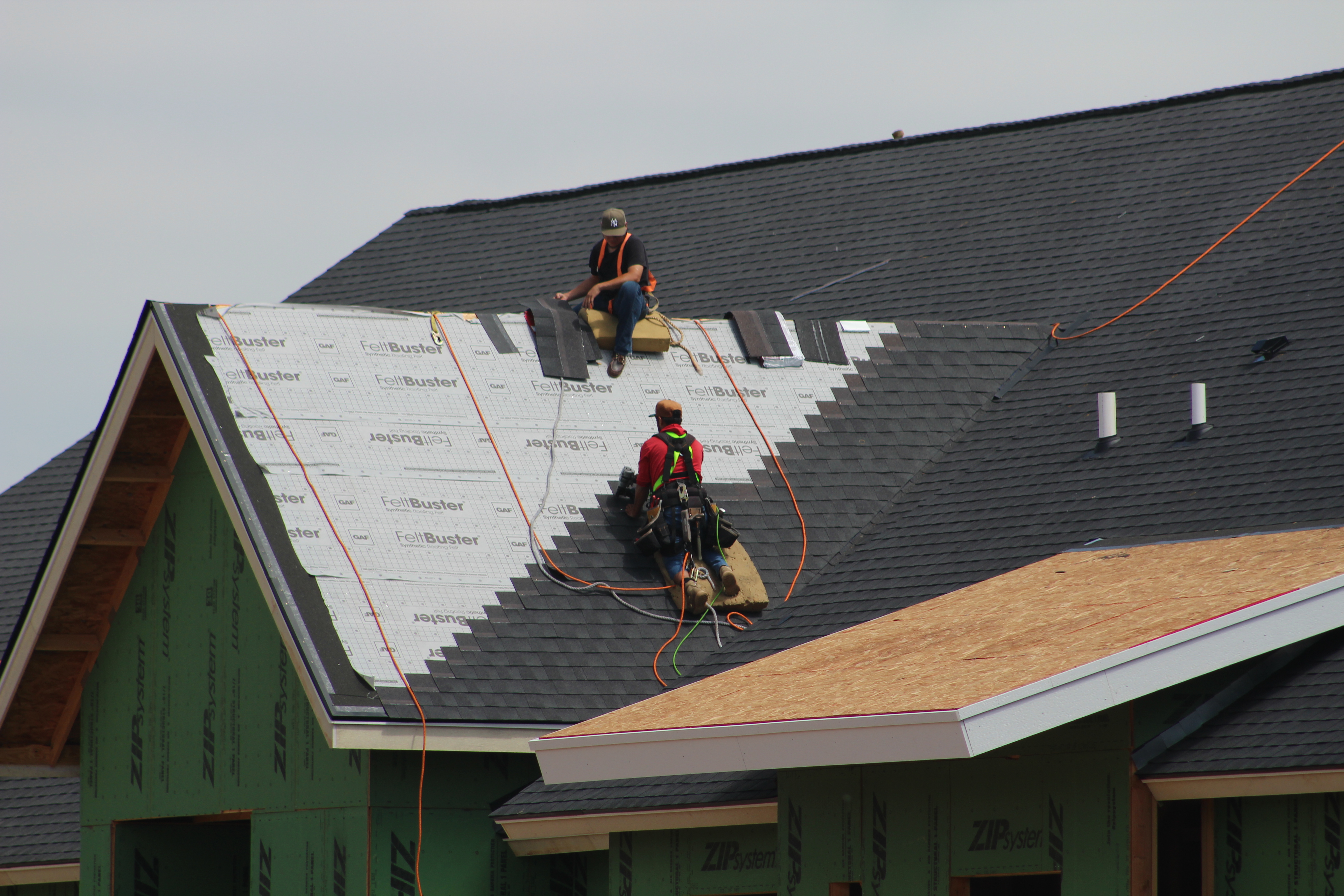 Two roofers actively working side by side