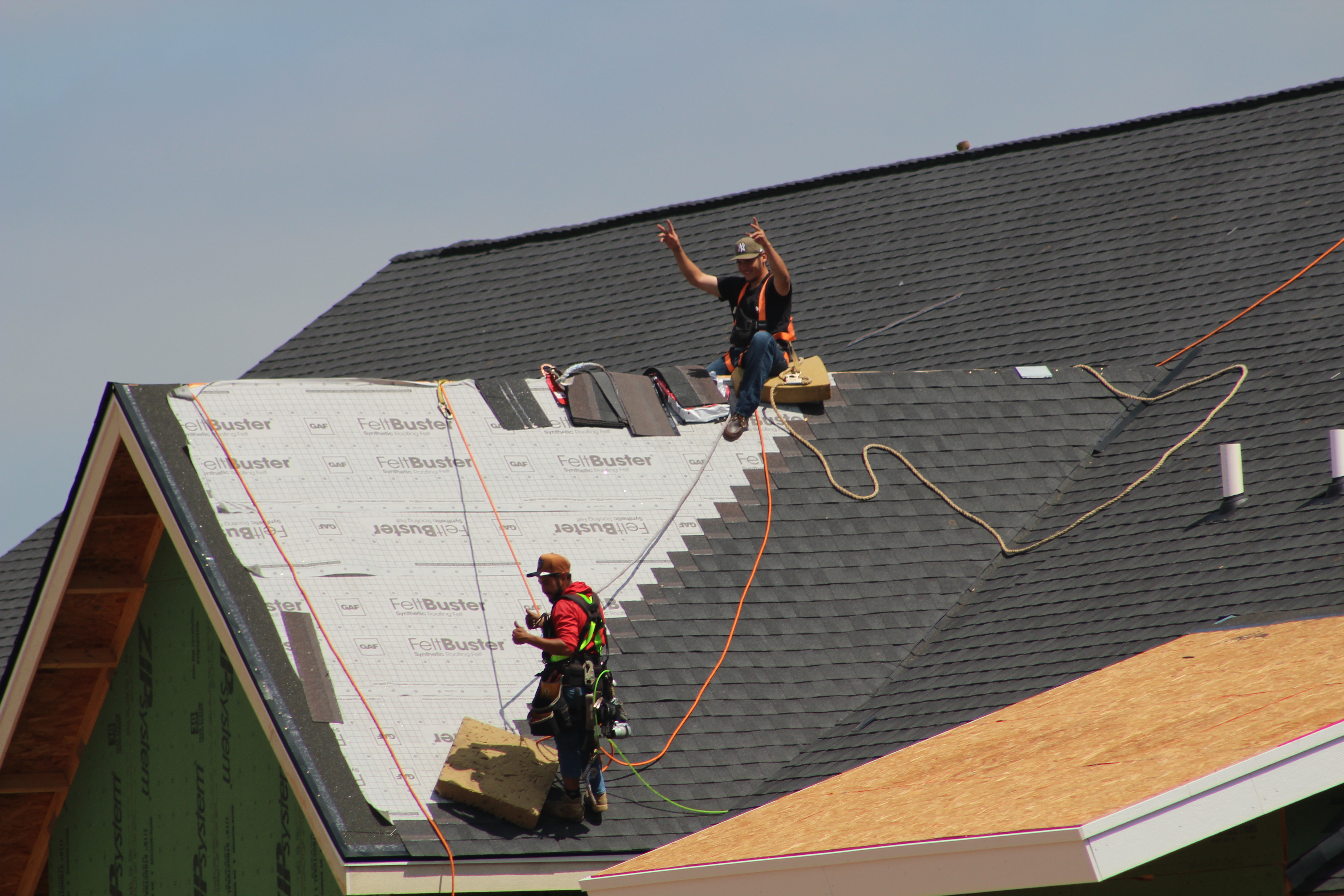 Premier Dwellings roofing crew waving from the peak